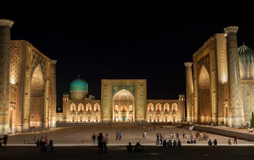 The tiled portals of Registan square in Samarkand, Uzbekistan, lit at night.
