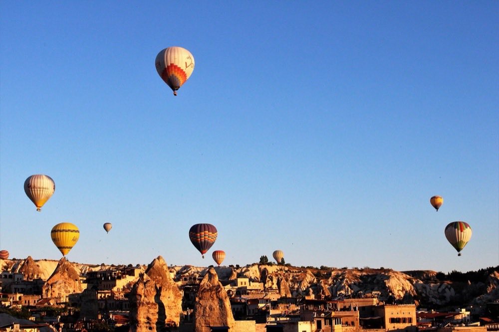 Hot air balloons rising over the rock houses and valleys of Goreme, Cappadocia.