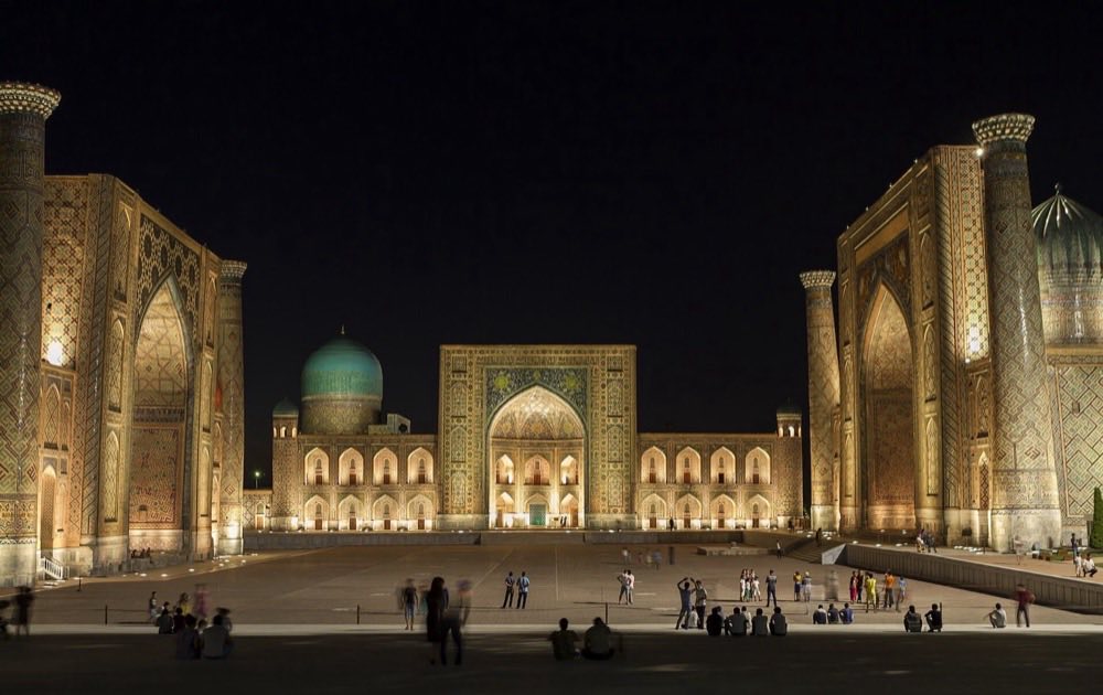 The tiled portals of Registan square in Samarkand, Uzbekistan, lit at night.